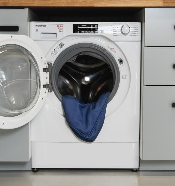 Washing machine with blue bolster cover coming out of the drum