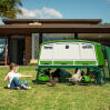 Little girl in a garden sitting next to the Eglu pro chicken coop with the under coop doors open